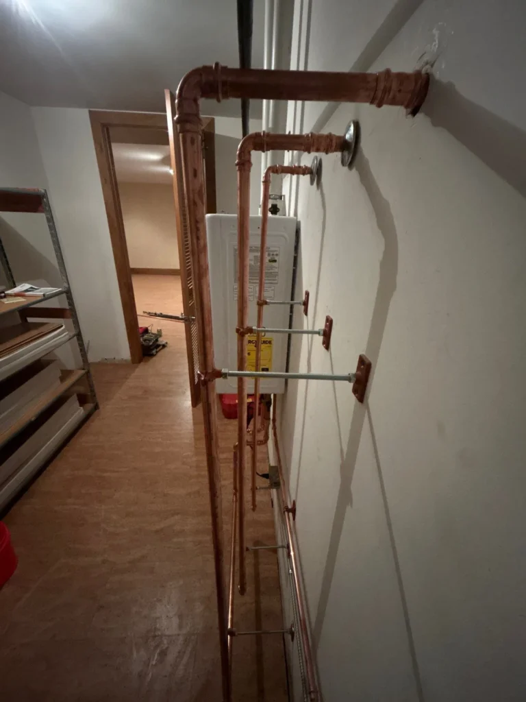 Side view of the same tankless install, showing the copper risers running the length of the wall