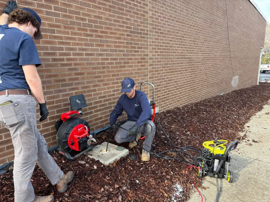 Two technicians running a sewer camera reel at a cleanout in Franklin