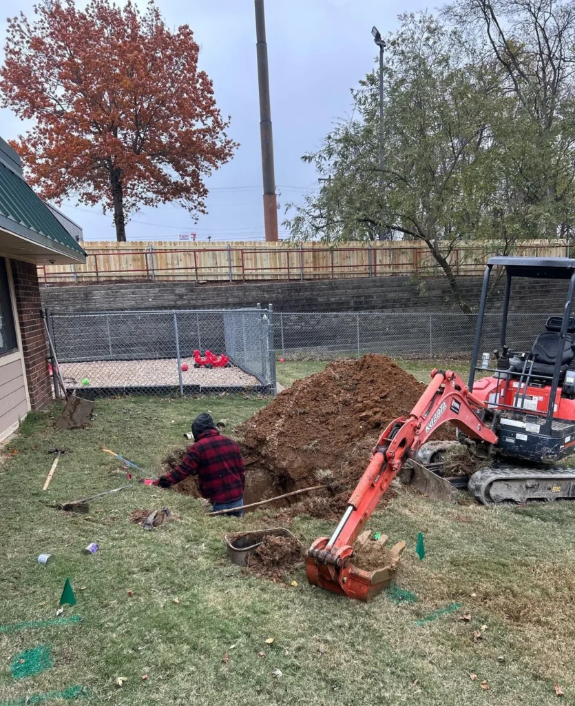 Excavator opening a trench for a commercial drain line repair in Mount Juliet