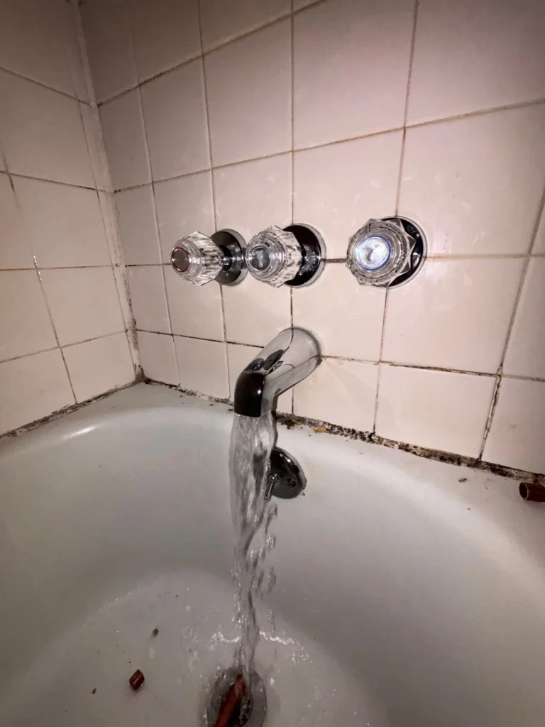Water running from a rebuilt three-handle tub and shower valve in Crieve Hall